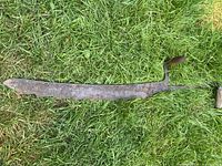 Overall view of hay saw lying on grass, showing full blade profile