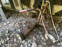 Full view of rusted metal tricycle on gravel