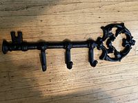 Front view of black cast iron key-shaped hanger showing ornate bow and four hooks