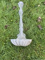 Front view of ornate cast metal wall planter with shell bowl