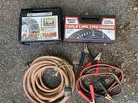 Overview of all items: extension cord, jumper cables, two tire chain sets