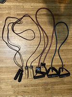 Two jump ropes and three resistance bands laid out on wood floor