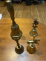 Four brass bells standing upright displaying varying sizes and finials
