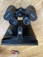 Binoculars resting on leather case, front eyepiece view
