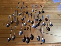 Full overhead view of all 30 souvenir flatware pieces laid out on wood floor