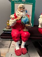 Santa with globe and magnifying glass seated on shelf edge