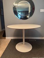 Full view of CB2 white round tulip table against wall