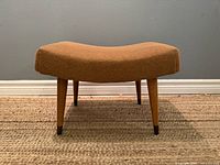 Front view of curved upholstered footstool