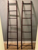 Two dark bamboo ladders standing upright against wall
