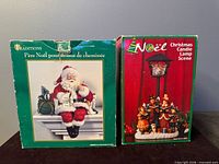 Two product boxes: Traditions Santa and Noël Candle Lamp Scene