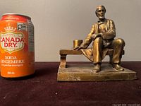 Front view of brass Abraham Lincoln figure beside soda can for scale