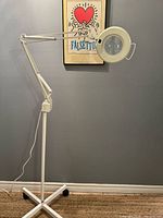 Full view of magnifying lamp with adjustable arm and wheeled base