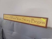 Wooden sign resting on couch showing full wording and coloration