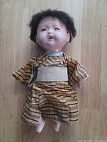 Front view of porcelain Ichimatsu doll in yellow plaid kimono