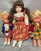 Group view of porcelain doll flanked by two Scottish dolls