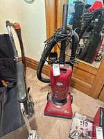 Front view of red Dirt Devil upright vacuum with hose and wand attached