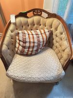 Front view showing tufted back, crochet seat cover, accent pillow, carved crest