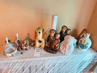Full lot showing bowl, bells, dog and child figurines, vases, medal