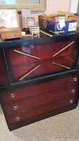 Front view showing black frame, burgundy fronts, brass pulls, X-style hardware