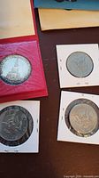 Group shot of four coins in holders and case
