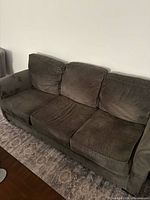 front view of the dark sage green three-seat couch showing overall design and cushions