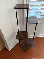 Full view of stand showing five wood shelves and black metal frame