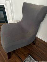 Front left view of grey slipcovered armless chair showing seat, backrest and wooden legs
