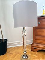 Full view of glass base table lamp with grey shade