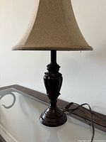 Full view of lamp showing dark brown base and attached beige fabric bell shade
