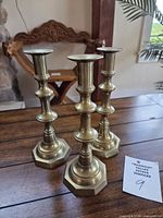 Three matching brass candlesticks on wooden surface