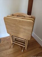 Front view of folded light oak TV trays on stand