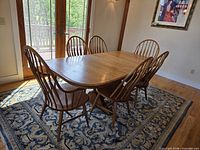 Dining table with six chairs shown on rug