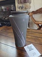 Front view of black matte pottery vase with pastel line accents and tag number 10 visible