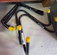 Four black V-shape brackets with yellow caps lying on floor