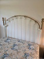 Headboard with brass rail and finials, mattress visible