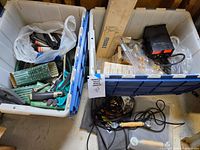 Overview of two totes with garden tools, downspout extenders, battery charger, cords