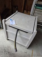 Exterior of grey Suncast hose reel box with hose exiting front slot