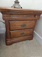 Front view of nightstand showing three drawers and hardware