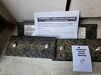 Pair of Rampends loading ramp brackets with instruction sheet visible