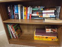 Two shelves showing board games and numerous books