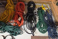 Row of coiled yellow, orange, black, green and blue cords on shelf