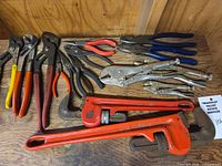 Group shot of all pliers and pipe wrenches on wooden surface