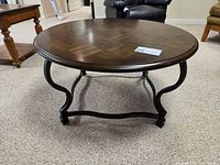 Full view of round coffee table showing wood top and metal base