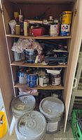 Full cabinet showing shelves of paint cans, tools, rags