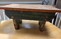 side view of stool showing green painted sides and legs