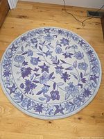 Full view of round blue floral wool rug on hardwood floor