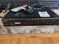 Front view of Sony DVP-NC80V with remote and cable on top