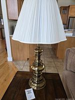Full view brass lamp with shade on wooden table