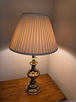 Full view of brass lamp with shade on tabletop