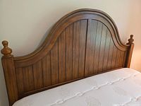 Arched wooden headboard with vertical planks and turned finials